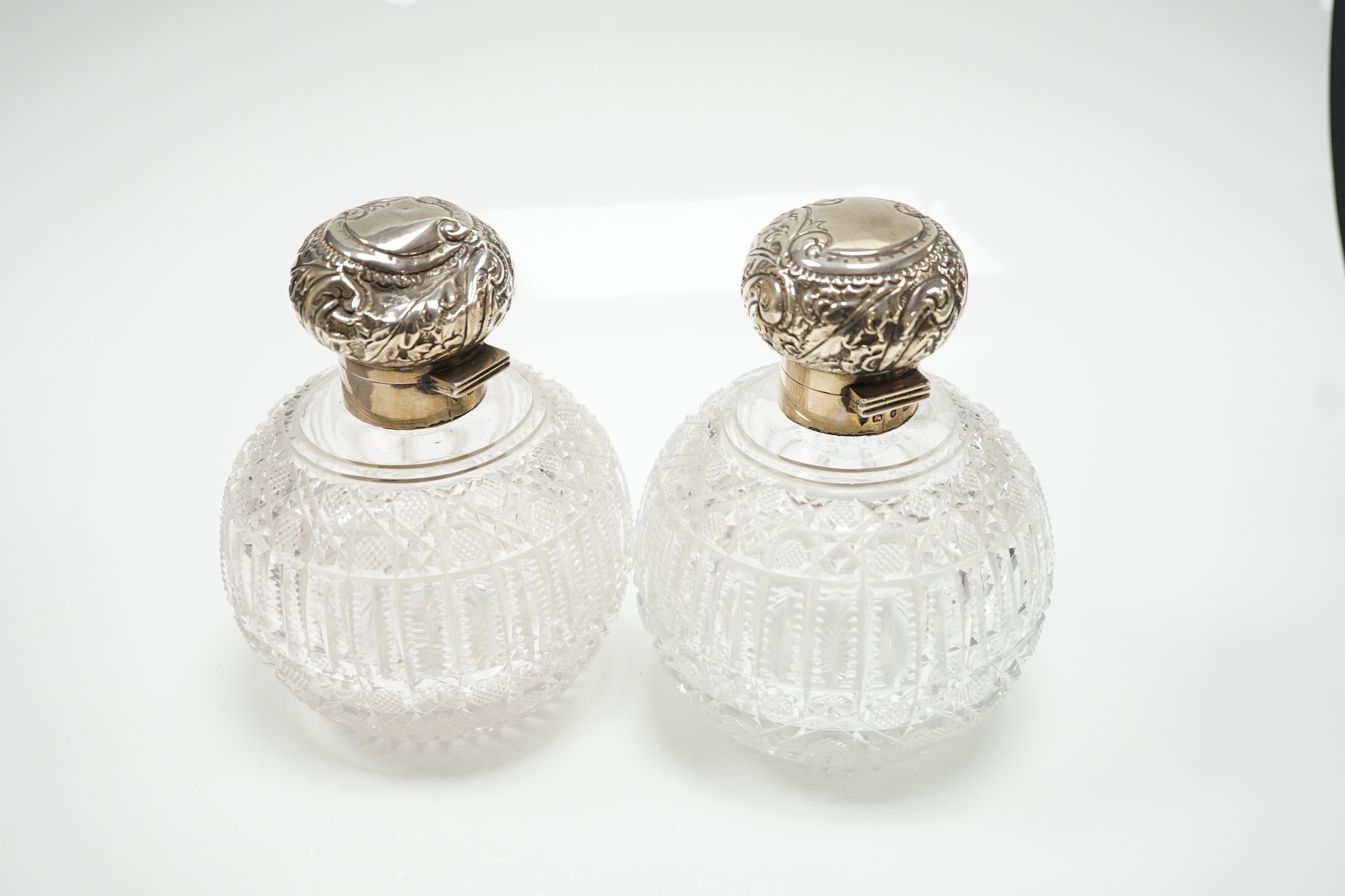 A pair of late Victorian silver mounted cut glass globular scent bottles (a.f.), Haseler Brothers, Birmingham, 1894/5, height 14.9cm.